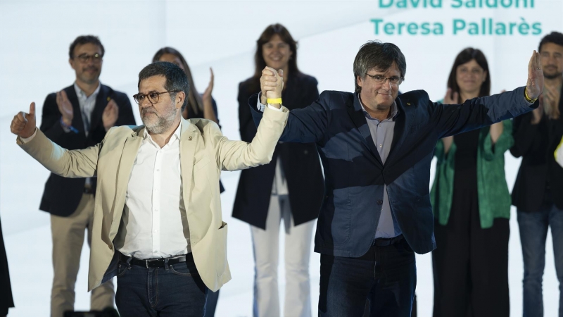 El secretario general de JxCat, Jordi Sànchez (i), toma de la mano al presidente de la formación, Carles Puigdemont (d), durante el segundo congreso de JxCat
