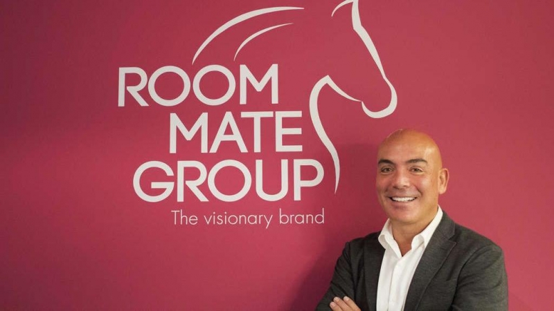 El empresario Kike Sarasola, junto al logo del grupo que aúna sus tres empresas, entre ellas la cadena hotelera que da nombre al grupo.