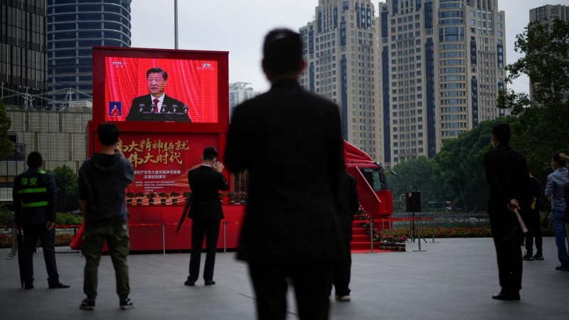 Varias personas miran una pantalla en una calle de Shanghai que muestra la intervención en vivo del presidente chino, Xi Jinping, en la ceremonia de apertura del 20º Congreso Nacional del Partido Comunista de China. REUTERS/Aly Song