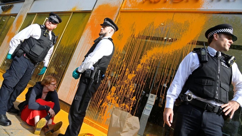 Agentes de policía detienen a un activista después de que se arrojara pintura sobre la ventana de una sala de exposición de automóviles durante una protesta 'Just Stop Oil' en Londres, Reino Unido, el 16 de octubre de 2022