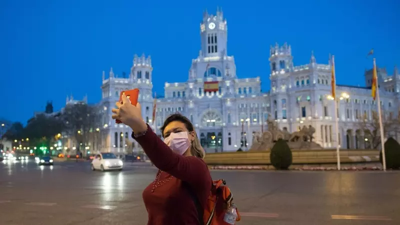Una joven con mascarilla se hace un selfi delante de la Cibeles en un Madrid prácticamente vacío en las primera horas del Estado de Alarma decretado por el Gobierno por el coronavirus. E.P./Joaquin Corchero
