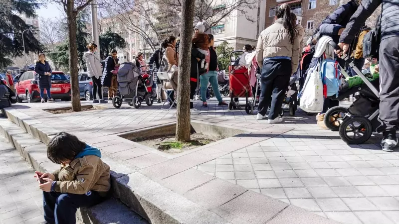 Un grupo de persona espera una cola durante la entrega de ropa de abrigo y zapatos nuevos a niños vulnerables, a 24 de febrero de 2023, en Madrid (España).