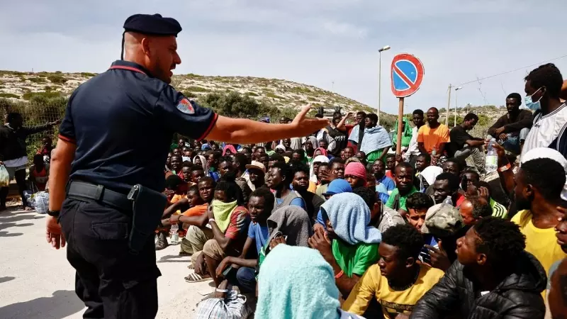 Un policía italiano habla a los migrantes que han llegado a la isla siciliana de Lampedusa, a 18 de septiembre de 2023