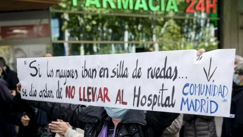 Una mujer sostiene una pancarta donde se lee 'Si los mayores iban en silla de ruedas... se dio la orden de no llevar al hospital', durante una concentración frente a la Asamblea de Madrid, a 4 de noviembre de 2021, en Madrid (España).