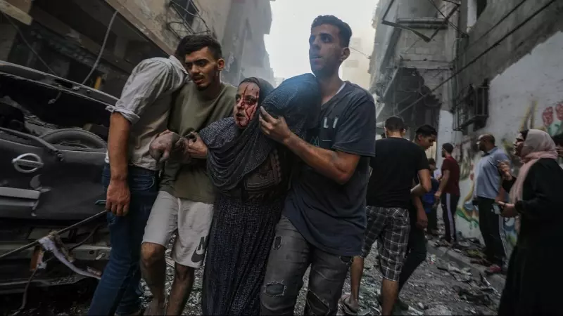 Una mujer recibe ayuda para salir de una zona bombardeada por Israel en el campo de refugiados de Al-Shati, en el oeste de la ciudad de Gaza, a 14 de octubre de 2023.
