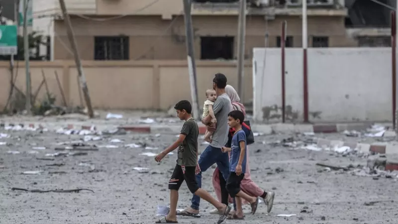 Una familia palestina camina frente a edificios destruidos por los ataques aéreos en la ciudad de Gaza