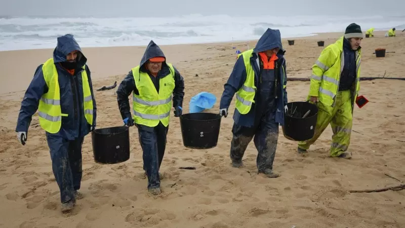 Operarios retiran los pellets o bolitas para fabricar plástico que han aparecido en las playas gallegas y de Asturias.