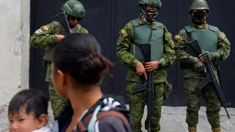 Una mujer camina por delante de un grupo de militares que vigilan la cárcel El Inca, en Quito, a 8 de enero de 2024.