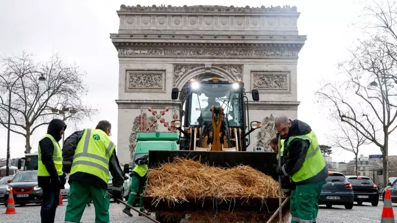 Los trabajadores municipales limpian paja arrojada por un tractor frente al Arco del Triunfo, en París, tras una protesta del sector agrario francés.