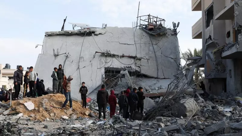 Un grupo de palestinos cerca de una casa derruida por un ataque israelí, en Rafah, en el sur de la Franja de Gaza. REUTERS/Ibraheem Abu Mustafa