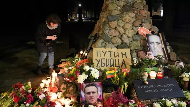 Una mujer se agacha para encender una vela, mientras la gente asiste a un evento conmemorativo, después de la muerte del líder de la oposición rusa Alexei Navalny en Vilna, Lituania.
