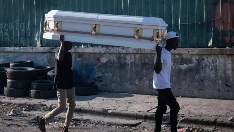 Dos hombres cargan un ataúd por una calle de Puerto Príncipe (Haití), tras los tiroteos.