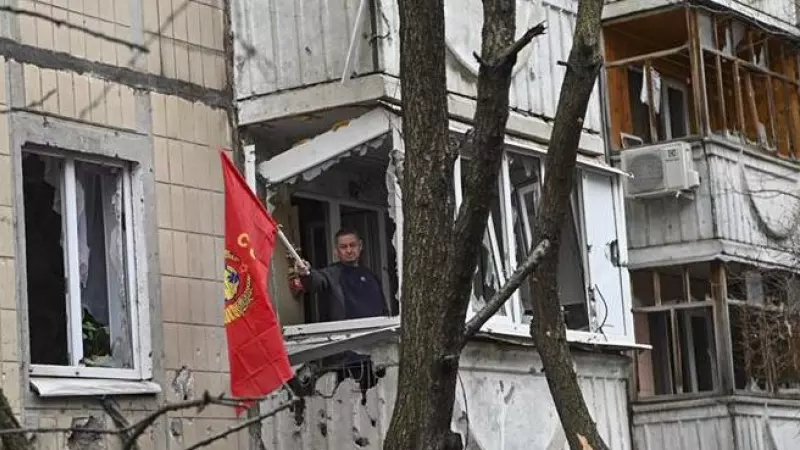 Un hombre ondeando una bandera roja desde el balcón de un edificio dañado tras un bombardeo en el centro de Belgorod, Rusia, el 16 de marzo de 2024.