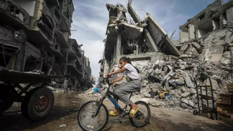 Una niña monta en bicicleta junto a edificios destruidos en una calle del campo de refugiados de Nuseirat (Franja de Gaza) el 5 de abril de 2024.