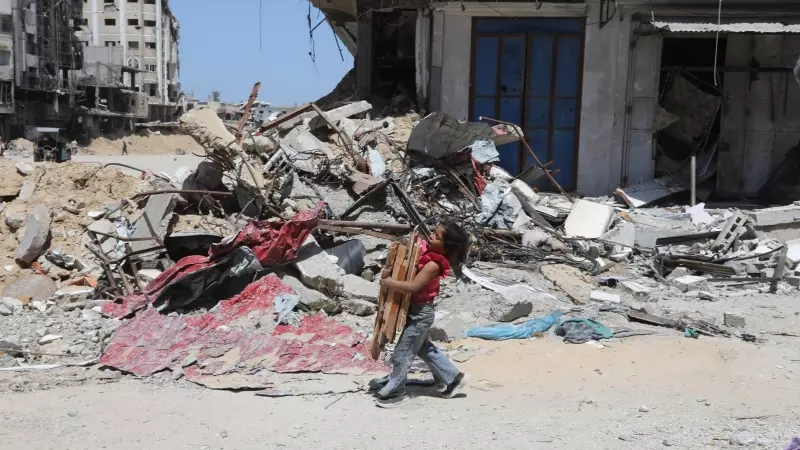 19/04/2924 Un niño palestino sostiene madera junto a las ruinas de edificios destruidos por los bombardeos israelíes, a 13 de abril de 2024.
