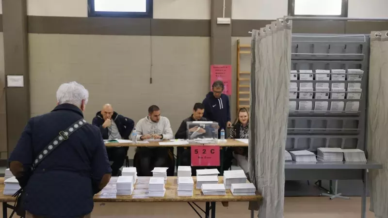 Un hombre escoge papeleta para ejercer su derecho al voto en un colegio electoral en Durango, Bizkaia