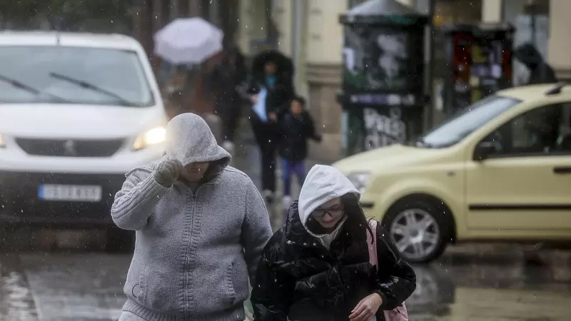 Foto de archivo de dos personas tapándose la cabeza con la capucha de la chaqueta como consecuencia de la lluvia