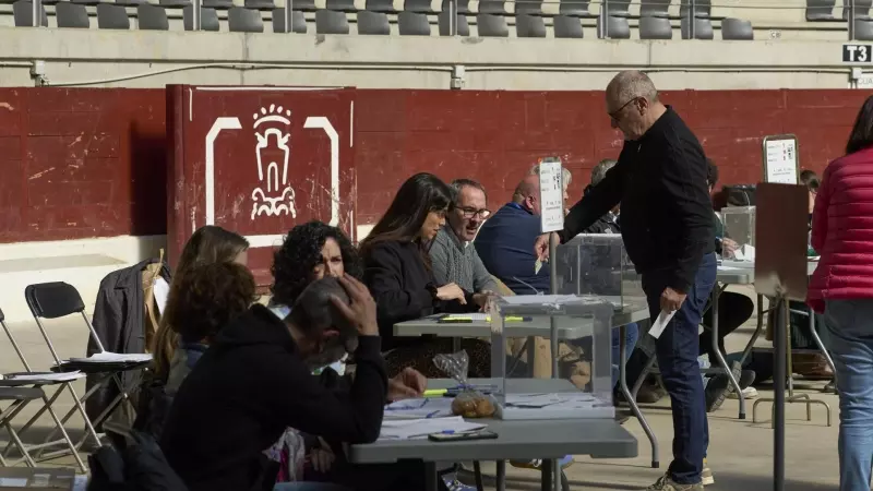 Un hombre ejerce su derecho al voto en el Iradier Arena, que antes era una plaza de toros detrás de una mesa electoral durante las elecciones vascas