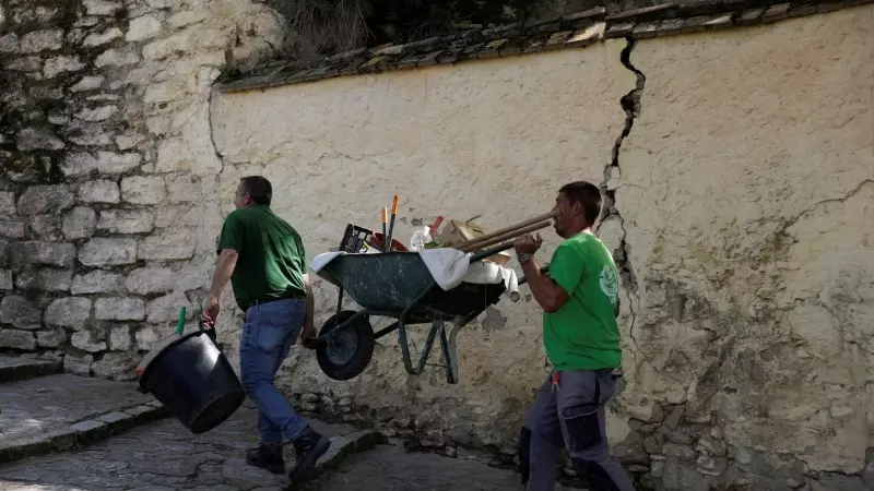 Un par de trabajadores cargan con una carretilla en una calle empinada de la localidad malagueña de Ronda. REUTERS/Jon Nazca