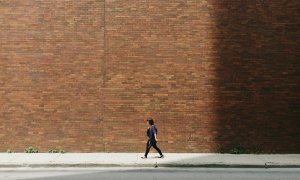 Una mujer camina junto a un muro de ladrillo.- Greg Shield / Unsplash