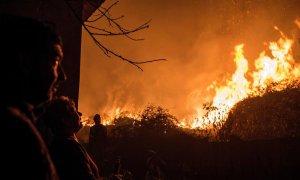 Los incendios están afectando especialmente a Galicia, donde han muerto cuatro personas. En la imagen, unos vecinos observan como se acerca a sus casas el incendio forestal de Carballeda de Avia (Ourense). - EFE