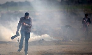 Un fotógrafo palestino trata de evitar el gas lacrimógeno lanzado por las fuerzas israelís. MOHAMMED ABED/AFP/Archivo