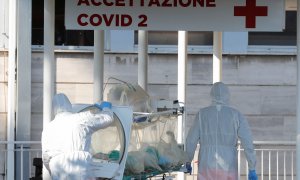 Dos sanitarios trasladan a un enfermo con coronavirus a un hospital en Roma./ REMO CASILLI (REUTERS)