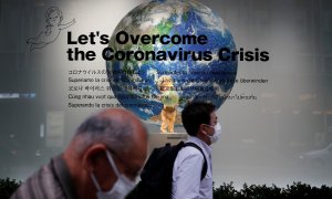 Dos peatones con mascarilla pasan por delantedel escaparate de unos grandes almacenes en Tokio, donde un cartel dice "Vamos a superar la crisis del coronavirus". REUTERS / Kim Kyung-Hoon