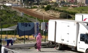 Una mujer recoge la ropa tendida junto a uno de los furgones. ROSA SOTO