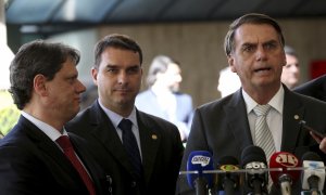 El presidente Jair Bolsonaro y su hijo mayor, el senador Flávio Bolsonaro, junto al ministro de infraestructuras, capitán Tarcísio Gomes de Freitas. WILSON DIAS/ AGÊNCIA BRASIL.