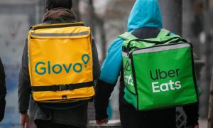 Un 'rider' de Glovo y otro de Uber Eats caminan por una calle principal .Reuters