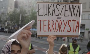 Una persona muestra un letrero en el que llama "terrorista" al presidente bielorruso, en Varsovia (Polonia). - Reuters