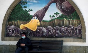 Un hombre con mascarilla sentado ante un grafiti de la Biblioteca Pública del Parque de San Francisco en el centro de Oviedo.