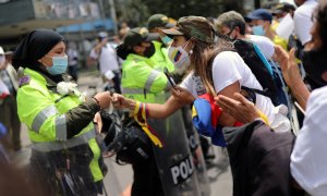 Una mujer golpea los puños con un oficial de policía mientras la gente marcha en oposición a los bloqueos de carreteras y la violencia después de un mes de protestas nacionales, en Bogotá, Colombia.