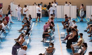 Multitud de jóvenes aguardan sentados tras recibir la vacuna contra el coronavirus en el pabellón municipal de Espartinas (Sevilla).