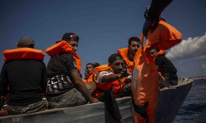 Un grupo de migrantes tunecinos reciben chalecos salvavidas de los socorristas de Open Arms a cuatro millas al sur de Lampedusa (Italia)