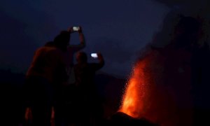 Cuatro personas contemplan desde una montaña al caer la noche la lava que sale del volcán de La Palma este lunes 20 de septiembre de 2021.