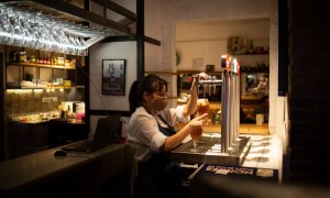 Una camarera sirve una cerveza en el interior de un bar en una calle céntrica de Barcelona