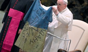 12/04/2022 - El papa Francisco muestra una bandera de Ucrania que fue enviada desde la localidad de Bucha durante la audiencia semanal en el Salón de Pablo VI en el Vaticano.