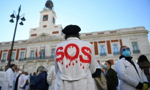 Un hombre con una bata donde se puede leer "SOS" en una concentración en defensa de la Atención Primaria, a 13 de noviembre de 2021, en Madrid