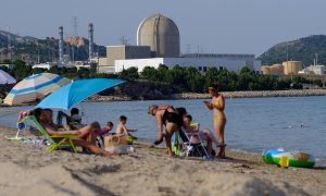 La central nuclear Vandellós II se ve al fondo mientras la se baña en la playa de la Almadraba en Hospitalet del Infante, en Tarragona.