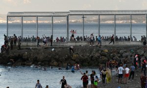 Personas migrantes caminan por la playa del Tarajal, el 17 de mayo de 2021, en Ceuta. E.P./Antonio Sempere