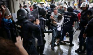 Un hombre intenta proteger a una mujer de los porrazos de agentes antidisturbios de la policía española el 1 de octubre de 2017.