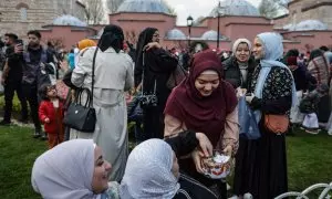 Una mujer ofrece dulces a otras mujeres musulmanas reunidas frente a la Mezquita Azul tras participar en las oraciones del Eid al-Fitr, en Estambul, a 21 de abril de 2023.