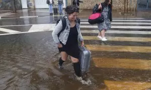 Varias personas cruzan una calle inundada cuando el episodio de lluvias torrenciales ha dejado un registro histórico de 198 litros por metro cuadrado esta madrugada en la ciudad de Castelló.