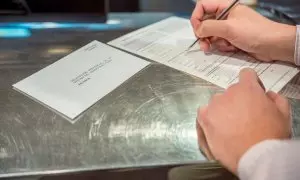 Una persona rellena unos documentos tras solicitar el voto por correo, en Madrid a 14 de junio de 2023