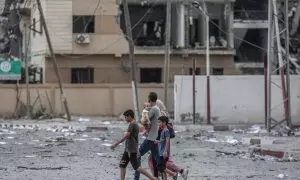 Una familia palestina camina frente a edificios destruidos por los ataques aéreos en la ciudad de Gaza