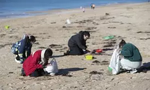 Voluntarios recogen microeplásticos o pellets, que han aparecido en toda la costa atlántica de Galicia, este domingo en la Playa de A Lanzada en O Grove.
