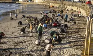 Varios voluntarios recogen pellets en la playa de Panxón, a 11 de enero de 2024, en Pontevedra.