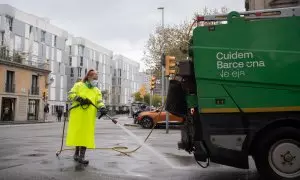 Una trabajadora de la limpieza riega una calle con una manguera en Barcelona, Catalunya.